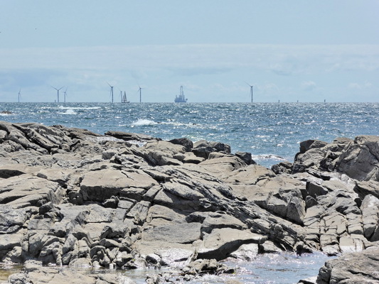 Ã©oliennes en mer au loin vues de la plage de rochers